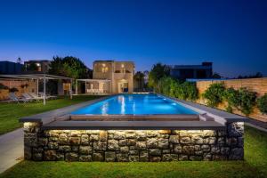 a swimming pool in the backyard of a house at night at Sea Homes Villas-Villa Sylvia in Kiotari