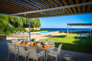 a table and chairs on a patio with a view of the ocean at Sea Homes Villas-Villa Sylvia in Kiotari +40 photos