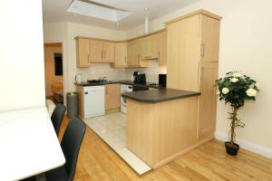 eine Küche mit Holzschränken und einer schwarzen Arbeitsplatte in der Unterkunft Eyre Square Apartment in Galway