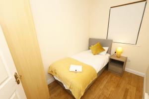 ein kleines Schlafzimmer mit einem Bett mit einer gelben Decke in der Unterkunft Eyre Square Apartment in Galway