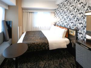 una stanza d'albergo con un letto, un tavolo e una finestra di APA Hotel Nihombashi Bakuroyokoyama Ekimae a Tokyo