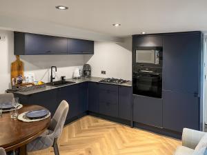 una cucina con armadi blu, un tavolo in legno e una sala da pranzo di Otter Hollow a Middleton