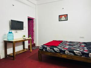 a bedroom with a bed and a table and a tv at Cozy haven in Auroville