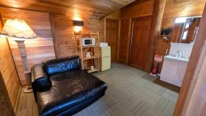 a living room with a leather couch and a lamp at Hakuba Loghouse in Hakuba