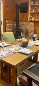 a wooden table with a bowl of fruit and wine glasses at Chalet GOROU in Hakuba