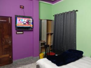 Jāmbにあるsky birds hotel & restaurantの紫色の壁とテレビとベッドのある部屋
