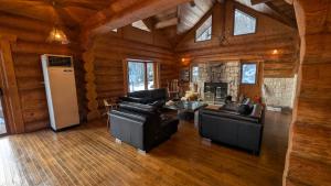 a living room with leather furniture and a fireplace at Hakuba Loghouse in Hakuba