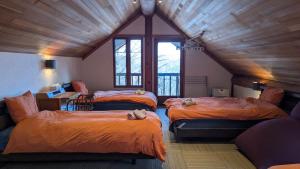 a room with three beds and a window at Hakuba Loghouse in Hakuba