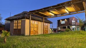 een klein huis met een rieten dak in een veld bij Alojamiento Los Nonos in Las Compuertas