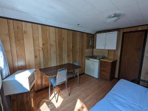 Tiny Wood Cottage 12 في واساغا بيتش: غرفه بطاوله وسرير ومطبخ