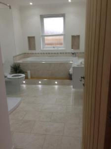 a bathroom with a tub and a toilet and a bath tub at Langley Cottage Retreat Sleeps 2 Long Stay 20-min to Banniskirk Hub in Wick +5 photos