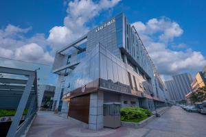 a tall glass building with a sign on it at Orange Nanjing Baijia Lake Xiaolongwan Subway Station Hotel in Jiangning