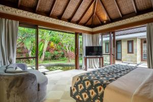 Forever Bali Villas في أُلُواتو: غرفة نوم مع سرير كبير وتلفزيون
