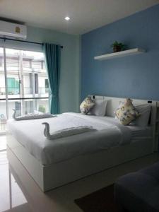 Un dormitorio con una gran cama blanca con ventana. en Kim Lung Airport Hotel, en Phuket