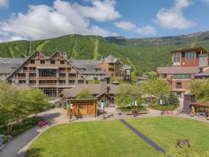 a resort with a park and mountains in the background at The Lodge at Spruce Peak, a Destination by Hyatt Residence in Stowe