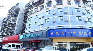 City Comfort Inn Wuhan Zongguan Metro Station في ووهان: مبنى ازرق فيه سيارات تقف امامه