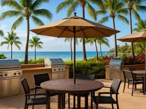 a table and chairs with an umbrella and the beach at The Westin Kāʻanapali Ocean Resort Villas-Ocean Front STUDIO VILLA in Lahaina