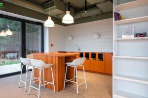 Una cocina con una isla naranja y taburetes blancos. en Studio apartment with gym, parking, coworking, en Maardu