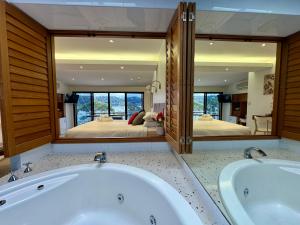 a large bathroom with two tubs and a bedroom at BlueWater Penthouse GuestSuite 2 in Newport +8 photos