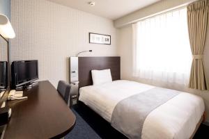 a hotel room with a bed and a desk at Comfort Hotel Saga in Saga