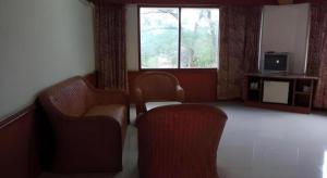 a room with two chairs and a tv and a window at Pailyn Hotel in Sukhothai