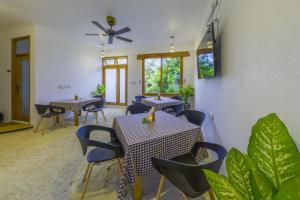 een eetkamer met tafels, stoelen en planten bij Ameera Maldives in Dhiffushi