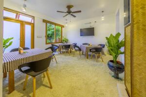 a dining room with tables and chairs and a tv at Ameera Maldives in Dhiffushi