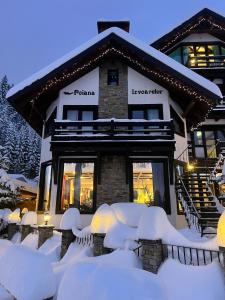 a building with snow covered chairs in front of it at Pensiunea Poiana Izvoarelor in Vatra Dornei