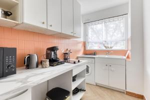 eine Küche mit weißen Schränken und einer Spüle in der Unterkunft Sienna Velvet Room - Balneo & Cinema - Ligne 9 in Montreuil + 45 Fotos