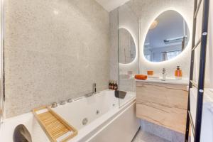 ein Badezimmer mit Badewanne, Waschbecken und Spiegel in der Unterkunft Sienna Velvet Room - Balneo & Cinema - Ligne 9 in Montreuil