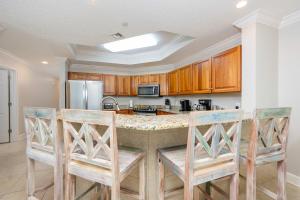 a kitchen with wooden cabinets and a island with chairs at Phoenix West 1002 in Orange Beach