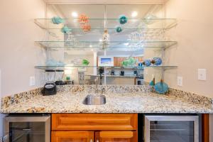 a kitchen counter with a sink and glass shelves at Phoenix West 1002 in Orange Beach