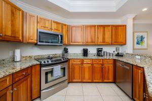 a kitchen with wooden cabinets and stainless steel appliances at Phoenix West 1002 in Orange Beach +47 photos