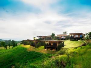 a group of houses on a grassy hill at Chantara Valley Resort in Ban Sap Bon