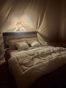 una cama blanca con una luz encima en ESCAPE cAMp, en Badīyah