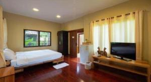 a bedroom with a bed and a flat screen tv at The Frog Khao Yai Resort in Ban Tha Chang