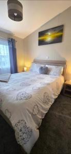 a bedroom with a large white bed with two teddy bears on it at Bay View Lodge in Heysham