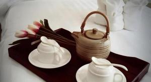 a table with two plates and a tea pot and flowers at Med Room Korat in Ban Pra Dok