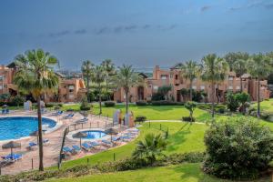 a resort with a swimming pool and palm trees and buildings at 2BR Ontspannen vakantiewoning in Casares