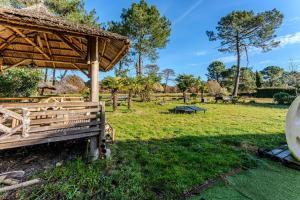 a wooden pavilion in a grass field with trees at Villa Saint Barth in Gujan-Mestras