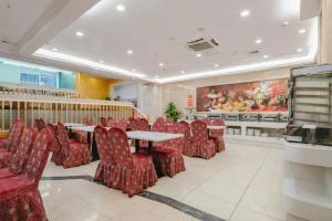Vienna Hotel Nanning Train Station في نانينغ: مطعم به كراسي وطاولات حمراء ولوحة فنية