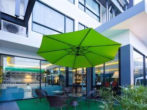 UDTel Boutique Hotel Udonthani في Ban Dong Kheng: مظلة خضراء على طاولة في مبنى
