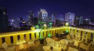 a balcony with tables and chairs and a city skyline at The Mou Hotel in Phnom Penh