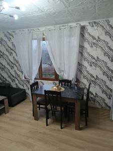 ein Esszimmer mit Tisch und Stühlen und einem Fenster in der Unterkunft Апартамент за гости Парадайс in Malko Tŭrnovo
