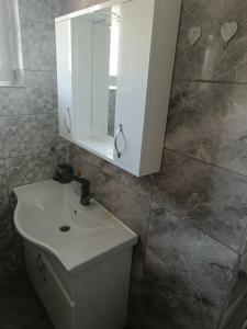 ein Badezimmer mit einem weißen Waschbecken und einem Spiegel in der Unterkunft Апартамент за гости Парадайс in Malko Tŭrnovo + 6 Fotos