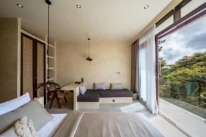 a bedroom with a bed and a desk and a window at Casa Beso Balangan in Badung