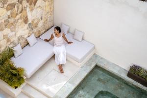 a woman in a white dress sitting on a couch next to a pool at Casa Beso Balangan in Badung