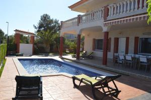 a swimming pool with chairs and a house at Vista Cunit in Cubelles