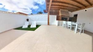 eine Außenterrasse mit weißen Stühlen und einer Bar in der Unterkunft La Maison de Montse - Piscine Privée in Corralejo + 33 Fotos
