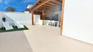 eine Terrasse mit weißen Stühlen und einer Bar an einem Gebäude in der Unterkunft La Maison de Montse - Piscine Privée in Corralejo